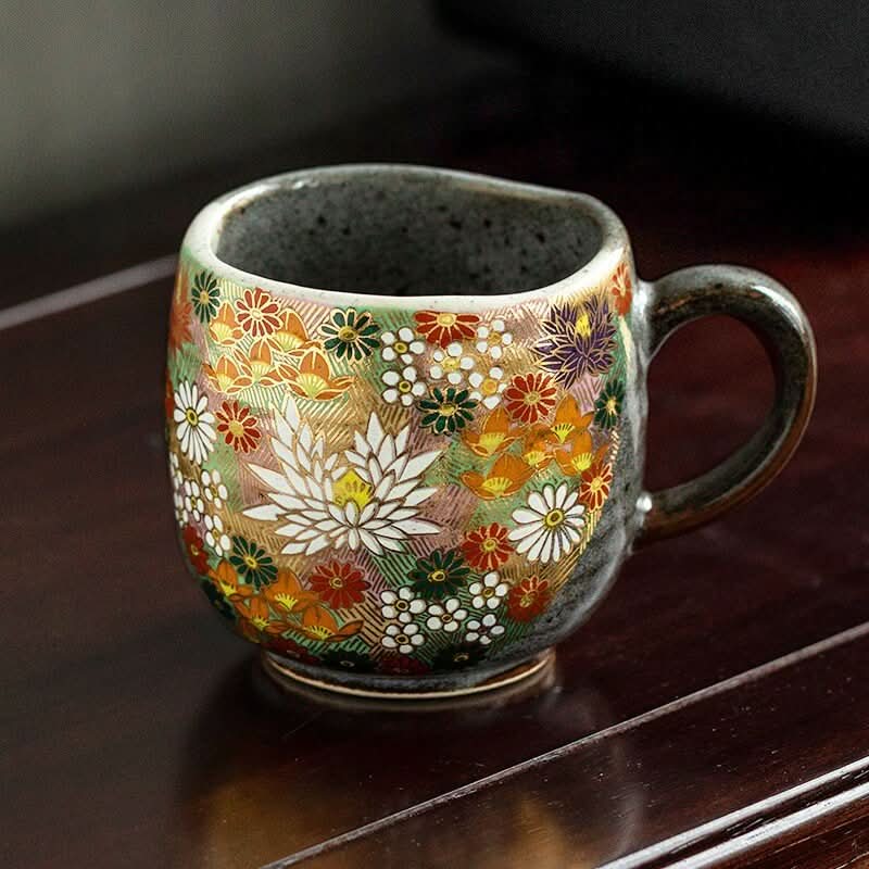 Kutani-yaki stoneware mug with vibrant floral pattern on dark wood.